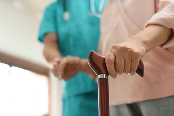 Medical worker taking care of elderly woman in geriatric hospice, closeup