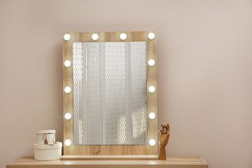 Stylish mirror with light bulbs near beige wall