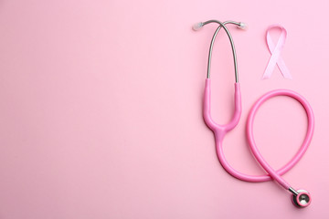 Pink ribbon as breast cancer awareness symbol and stethoscope on color background, flat lay. Space...