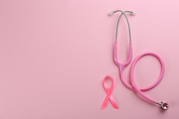 Pink ribbon as breast cancer awareness symbol and stethoscope on color background, flat lay. Space for text