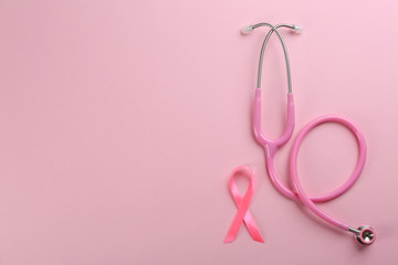 Obraz na płótnie Canvas Pink ribbon as breast cancer awareness symbol and stethoscope on color background, flat lay. Space for text