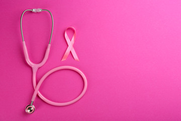 Obraz na płótnie Canvas Pink ribbon as breast cancer awareness symbol and stethoscope on color background, flat lay. Space for text