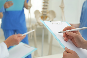 Female orthopedist with clipboard in clinic, closeup