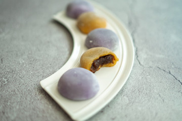 Multi-colored Japanese Mochi in rice dough and on a beautiful plate and concrete background. Traditional Japanese dessert.