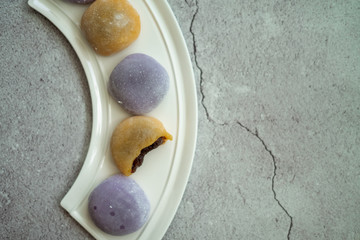 Multi-colored Japanese Mochi in rice dough and on a beautiful plate and concrete background. Traditional Japanese dessert.