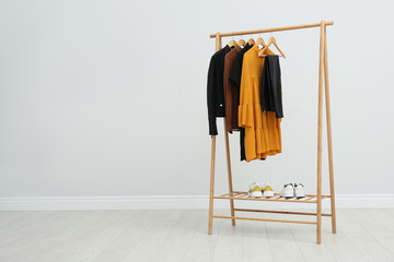 Wooden rack with stylish clothes in room. Space for text