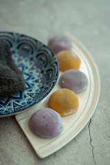 Multi-colored Japanese Mochi in rice dough and on a beautiful plate and concrete background. Traditional Japanese dessert.