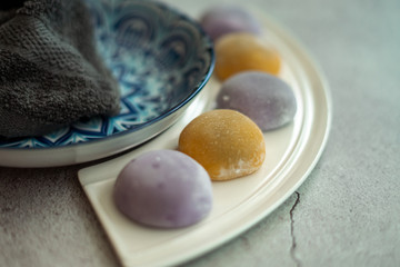 Multi-colored Japanese Mochi in rice dough and on a beautiful plate and concrete background. Traditional Japanese dessert.