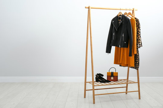 Wooden rack with stylish clothes in room. Space for text