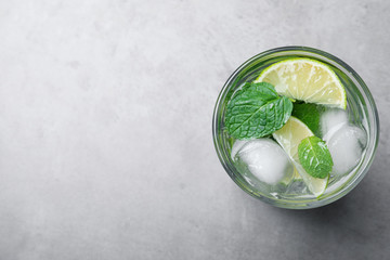 Glass of fresh Mojito cocktail on grey table, top view. Space for text