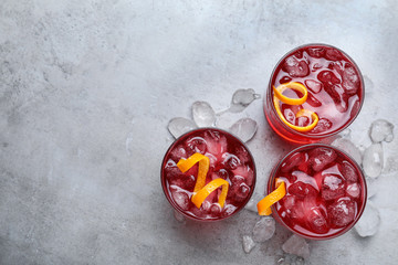 Fresh Negroni cocktails with orange zest on grey table, flat lay. Space for text