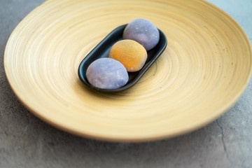 Obraz na płótnie Canvas Japanese Mochi in rice dough and on a beautiful bamboo plate and concrete background. Traditional Japanese dessert.