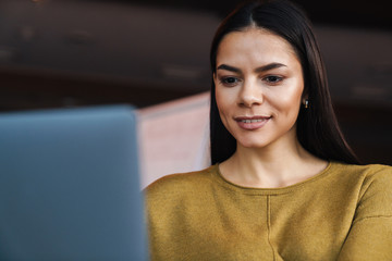 Image of young caucasian businesswoman working on laptop in office