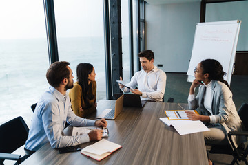 Image of young female and male colleagues working on laptops in office