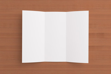 Blank opened tri fold brochure on wooden background