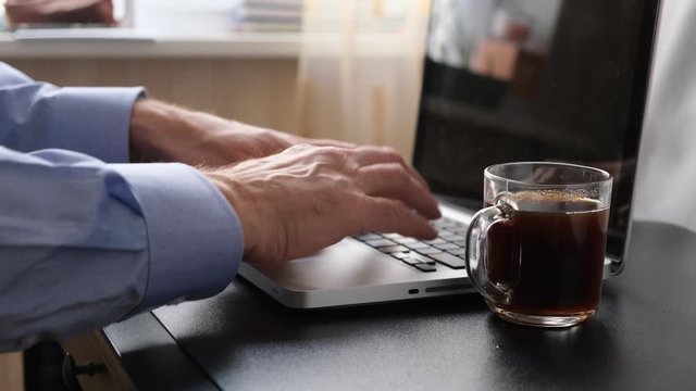 computer keyboard, a man types on a computer and drinks coffee