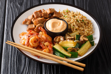 Serving hibachi of rice, shrimp, steak and vegetables served with sauce closeup in a plate. horizontal