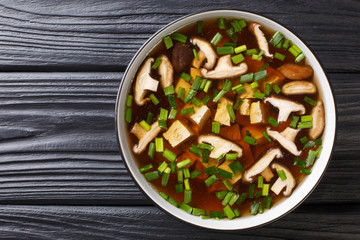Asian soup with shiitake mushrooms, tofu cheese and green onions close-up in a bowl. Horizontal top view