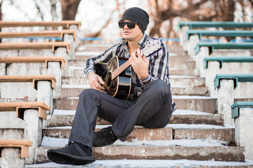 Young man sitting on steps playing guitar and singing, music concept