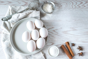 Fototapeta na wymiar Baking ingredients. White eggs in a plate with napkin on white wooden background. Easter composition, mockup. Bakery background frame.