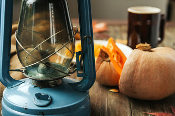 Blue kerosene lamp on an old wooden table and slices of pumpkin.