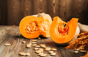  Pumpkin slices, pumpkin seeds and autumn leaves on an old wooden table.