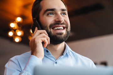 Portrait of businessman talking on cellphone while working in office