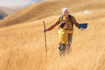 Senior man with grandson on country walk in autumn.