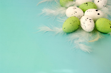 Green quail eggs on feathers, angle composition, happy easter banner, greeting card design, flatlay style. Food photo.