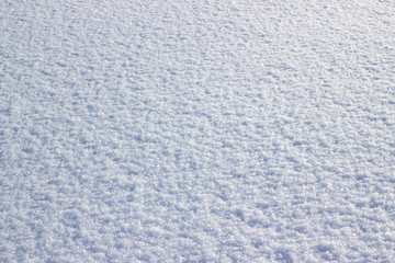 Real white snow surface. Background of fresh snow. Texture of blue snow sparkling in the sun.