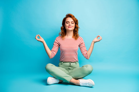 Full size photo of quiet serene woman sit floor crossed legs show om sign exercise yoga meditation wear stylish green outfit isolated over blue color background