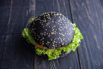 Gourmet black burger with Spicy sauce on wooden table and black background