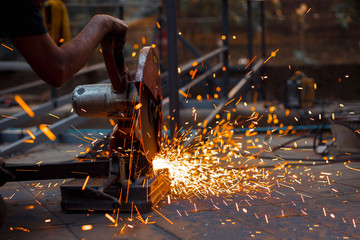 A Worker cutting metal with grinder.