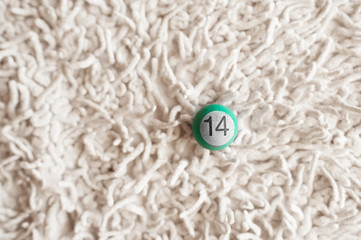 a small billiard ball of green and mint color with the number 14 on a fuzzy uneven light background