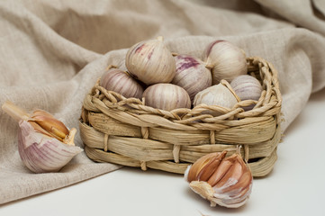 garlic solo in a wicker basket on a linen background.next to it is a canvas bag. eco condiments