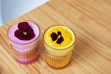 Fancy colorful latte with pink and yellow milk foam in glass cups
