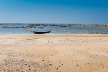 Longboat on beach with rocks in background