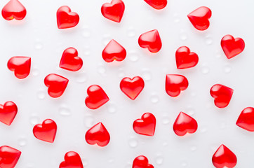 white background with red hearts pattern and water drops, flat lay
