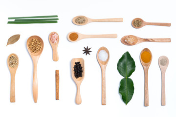 Various spices in wooden spoons, isolated background