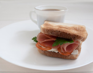 sandwich with sausage and tomatoes on a white plate