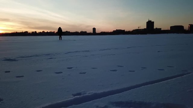 Couple/ friends playing/ walking on a frozen lake during blue hour