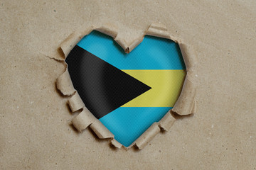 Heart shaped hole torn through paper, showing Bahama flag