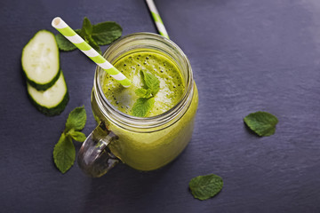 Healthy green smoothie in glass jar on black table close-up.