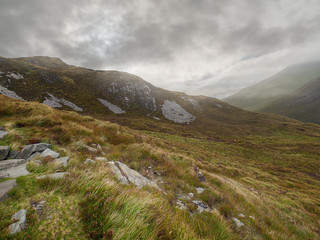 Fototapeta na wymiar Mountains in Connemara, county Galway, Stone patches in grass land, Cloudy sky. Nobody.
