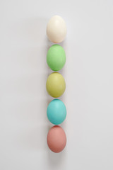 Five multicolored easter eggs lie in a straight line. White background for lettering and design. Copy space for your text