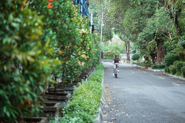 Asian young woman goes wearing a helmet and a bag riding her folding bicycle on the road