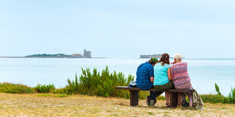 Family vacation in Normandy, France. Senior woman, her adult daughter and grandson (back view;...