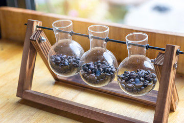Fresh coffee beans in glass bottles placed on a wooden table at the coffee shop.