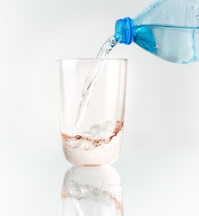 Pouring water from blue bottle into glass