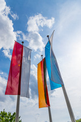 Die Flaggen von Deutschland, Bayern und Unterfranken wehen im Wind vor weißblauem Himmel